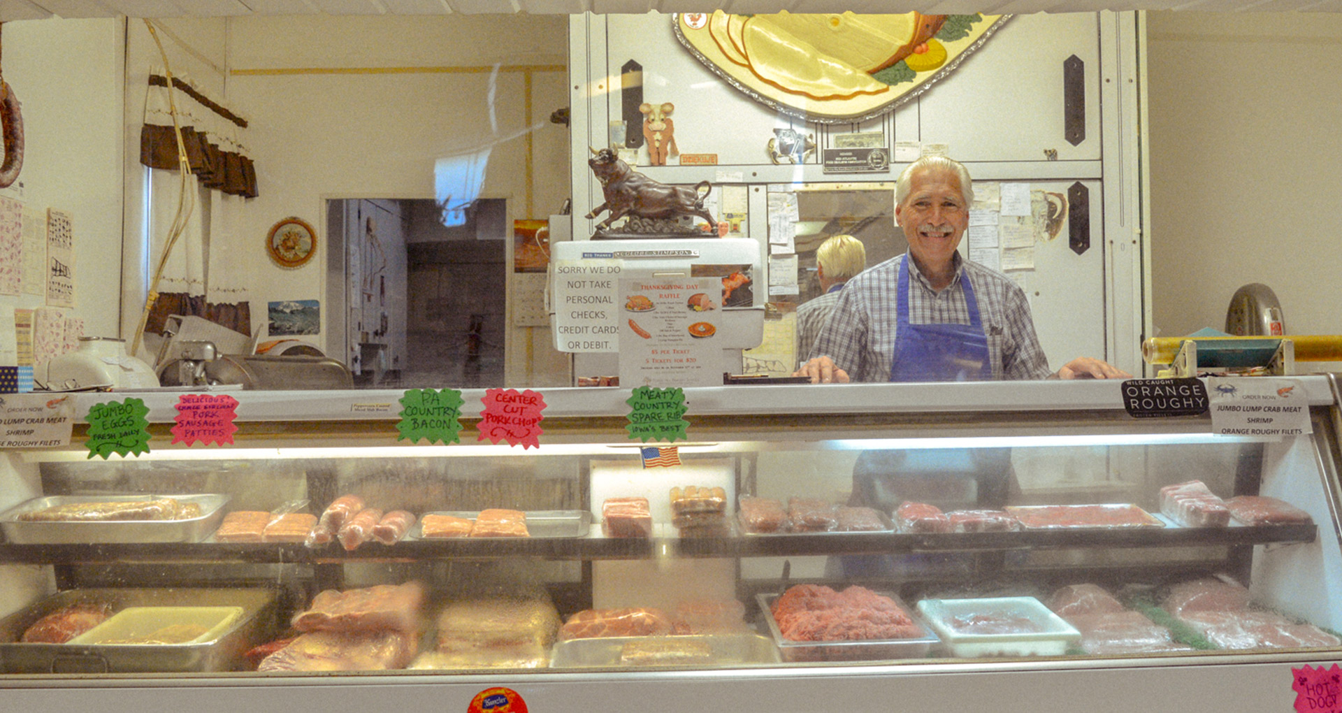 Dudek smiling and standing behind the meat counter greeting customers