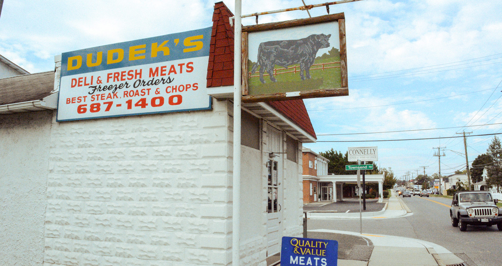 view of the outside of the butcher shop with Dudek's sign and painted image of a cow